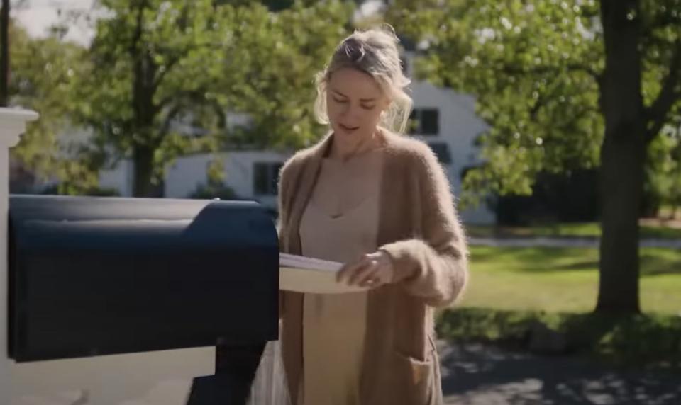 In a scene from 'The Watcher' Naomi Watts looks down at letters as she pulls them from a mailbox