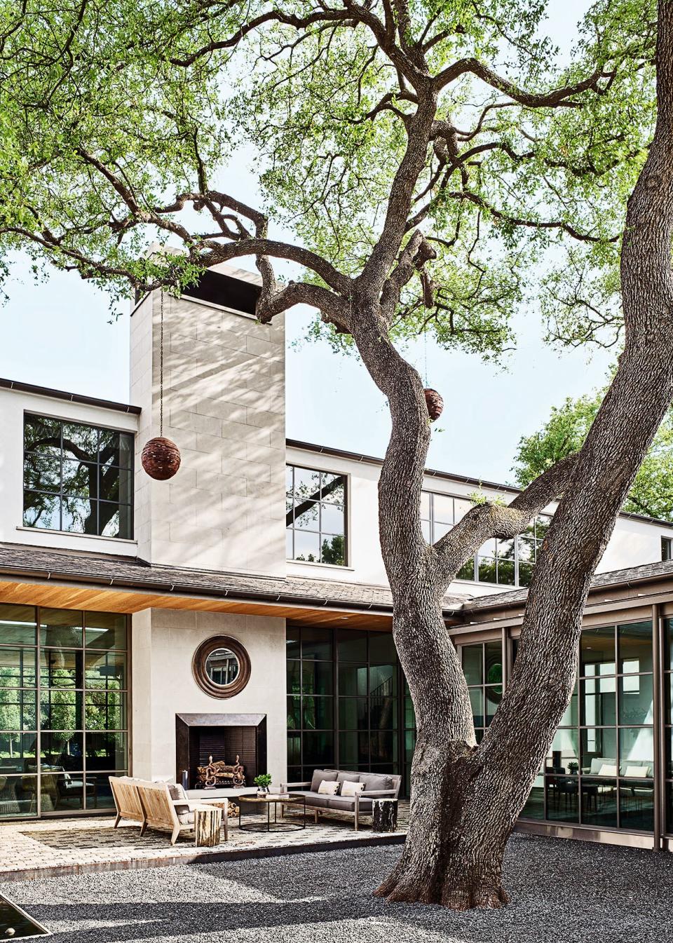 The property’s live oak is framed within a central courtyard; the mirror and cocktail table are by Arteriors.