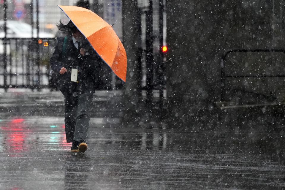 A person walks at a street in the snow Monday, Feb. 5, 2024, in Tokyo. Japan Meteorological Agency warns more metropolitan areas braced for snowfall Monday. (AP Photo/Eugene Hoshiko)