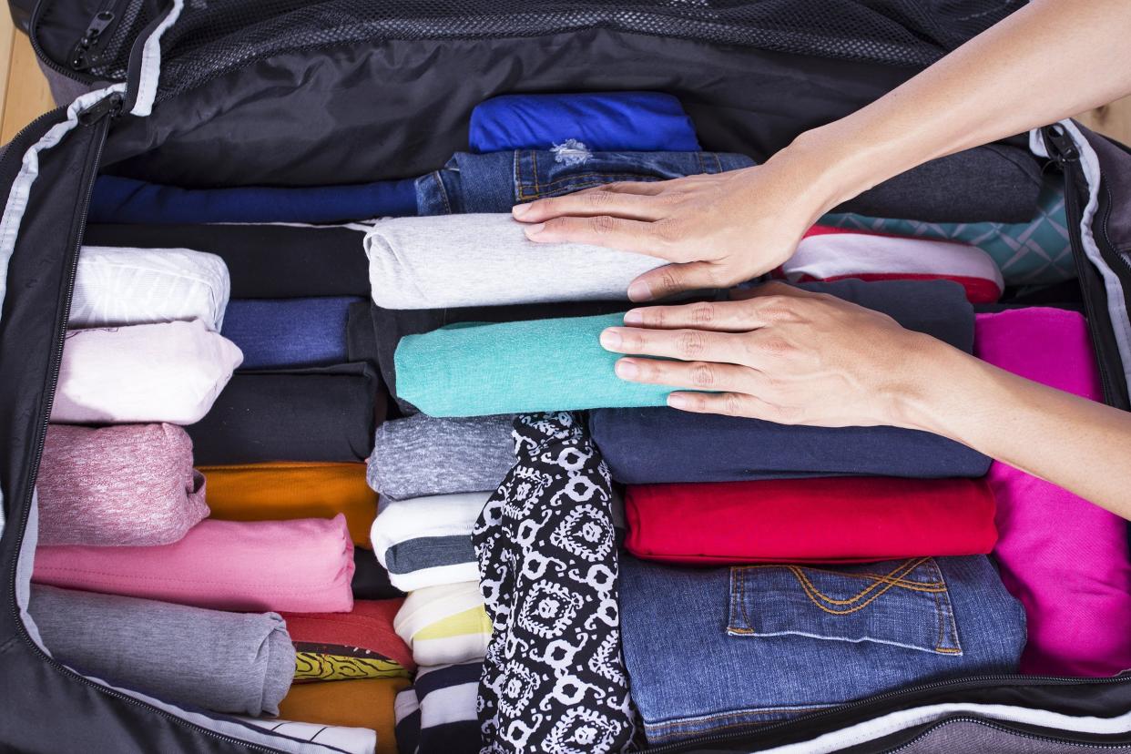 a woman packing clothes in a suitcase