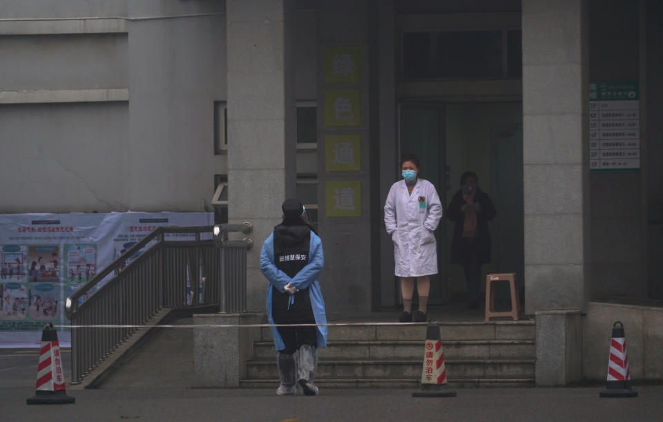 Hospital staff stand outside the emergency entrance of Wuhan Medical Treatment Center, where some infected with a new virus are being treated, in Wuhan, China, Wednesday, Jan. 22, 2020. The number of cases of a new coronavirus from Wuhan has risen to over 400 in China health authorities said Wednesday. (AP Photo/Dake Kang)