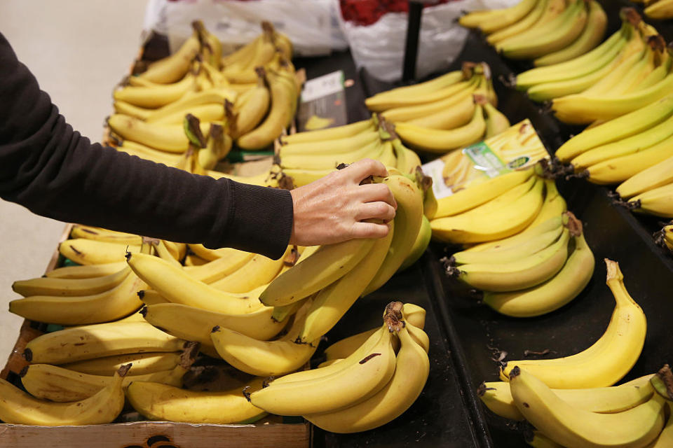 A Woolworths customer reaches for a bunch of bananas on the shelf. Source: Getty