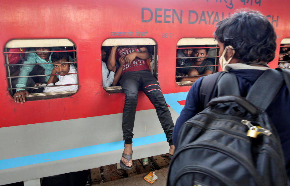 A migrant worker tries to board an overcrowded passenger train from an emergency window, after government imposed restrictions on public gatherings in attempts to prevent spread of coronavirus disease (COVID-19), in Mumbai, India, March 21, 2020. REUTERS/Prashant Waydande TPX IMAGES OF THE DAY