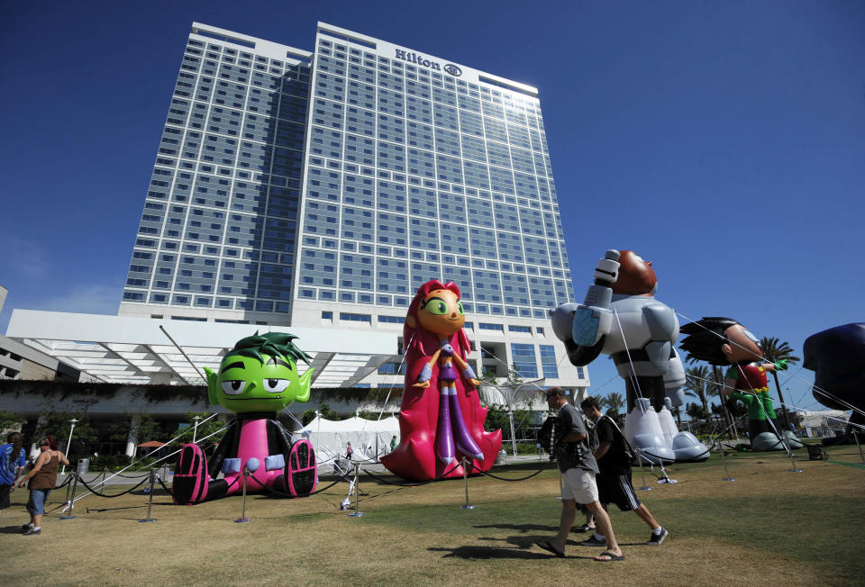 Fans walks past blow up Team Titans figures outside the San Diego Convention Center as they head to the Preview Night event on Day 1 of the 2013 Comic-Con International Convention on Wednesday, July 17, 2013, in San Diego. (Photo by Denis Poroy/Invision/AP)