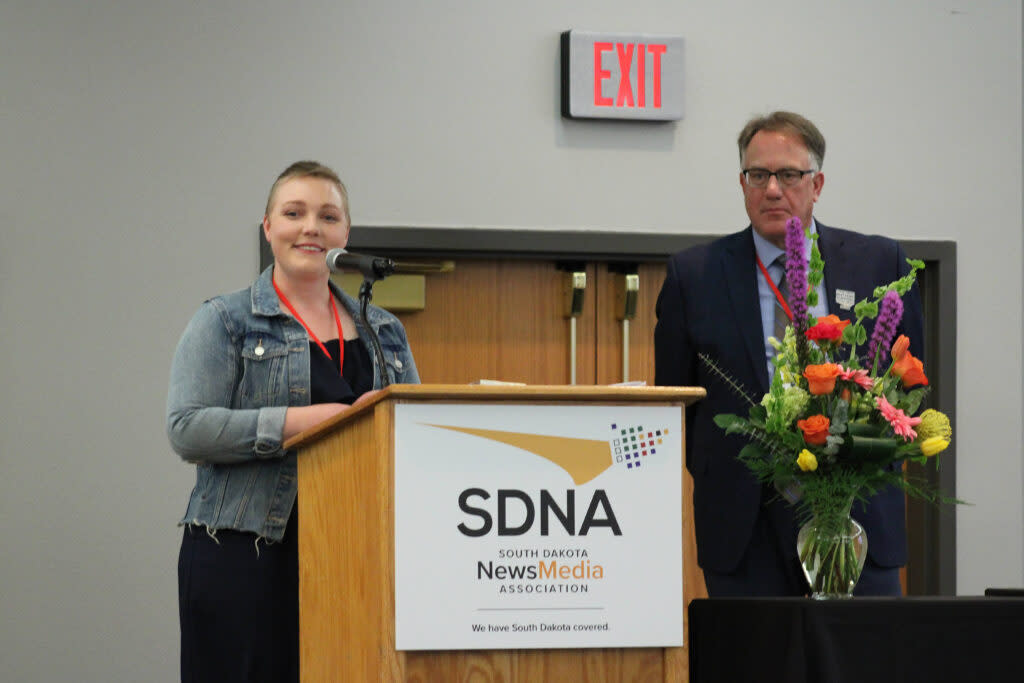 Makenzie Huber, reporter for South Dakota Searchlight, addresses the crowd April 26, 2024, at the South Dakota NewsMedia Association convention in Huron while accepting the 2023 Outstanding Young Journalist award from the association's executive director, David Bordewyk. (Seth Tupper/South Dakota Searchlight)