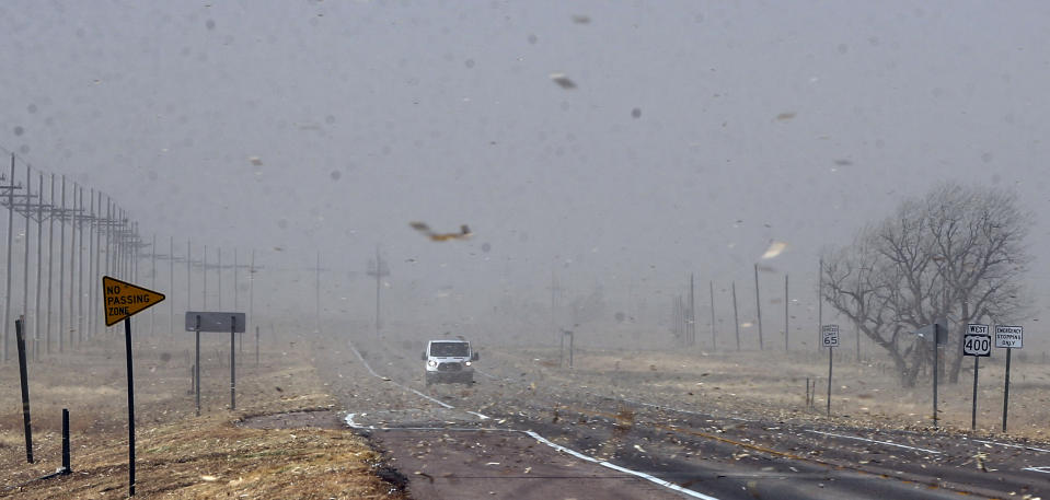 Debris from nearby farm fields swirls around on Highway 400 between Mullinville, Kans., and Dodge City on Wednesday, Dec. 15, 2021. (Travis Heying/The Wichita Eagle via AP)