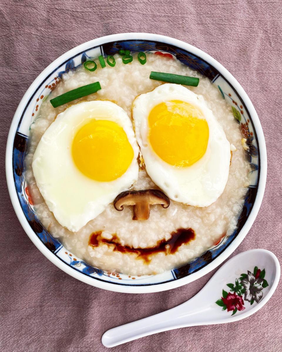 a bowl of congee with two friend eggs arranged in a smiley face