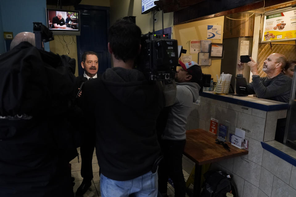 Chicago mayoral candidate Rep. Jesus "Chuy" Garcia, D-Ill., talks to reporters after lunch at Punta Cana restaurant as owner Yonny Mora, left, make a photo of the group Wednesday, Feb. 22, 2023, in Chicago. Garcia, who continues to seek the mayor's office, forced then-Mayor Rahm Emanuel to a runoff in 2015. (AP Photo/Charles Rex Arbogast)