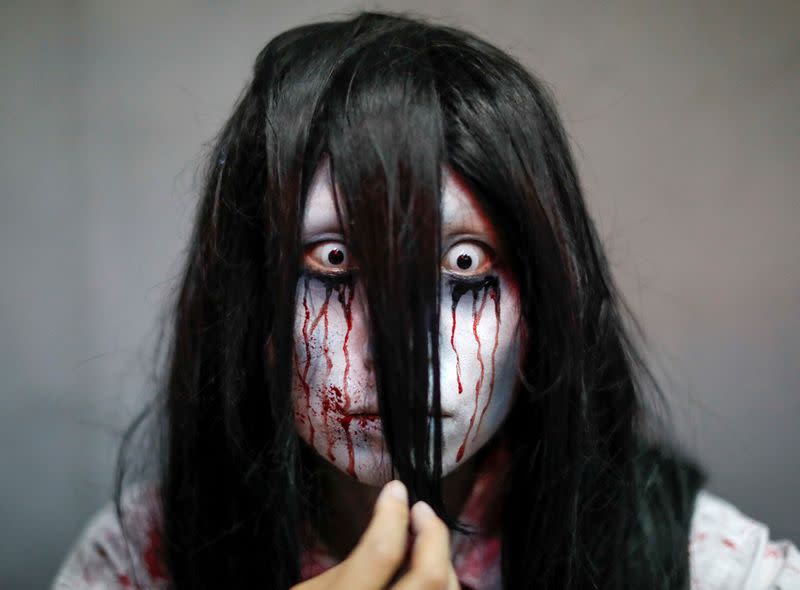 An actor dressed as a zombie is seen before their performance at a drive-in haunted house show by Kowagarasetai, in Tokyo