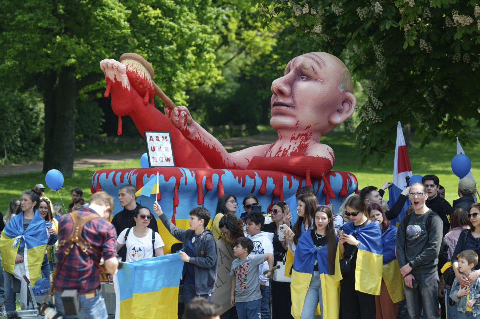People stay in front of a carnival figure of Russian President Putin as they take part in a protest ralley against protests against arms deliveries to Ukraine in Aachen, Germany, Sunday, May 14, 2023. On Sunday afternoon Ukrainian President Volodymyr Zelenskyy and the Ukrainian people are to be honored in Aachen with the Charlemagne Prize for services to the unity of Europe. (Henning Kaiser/dpa via AP)