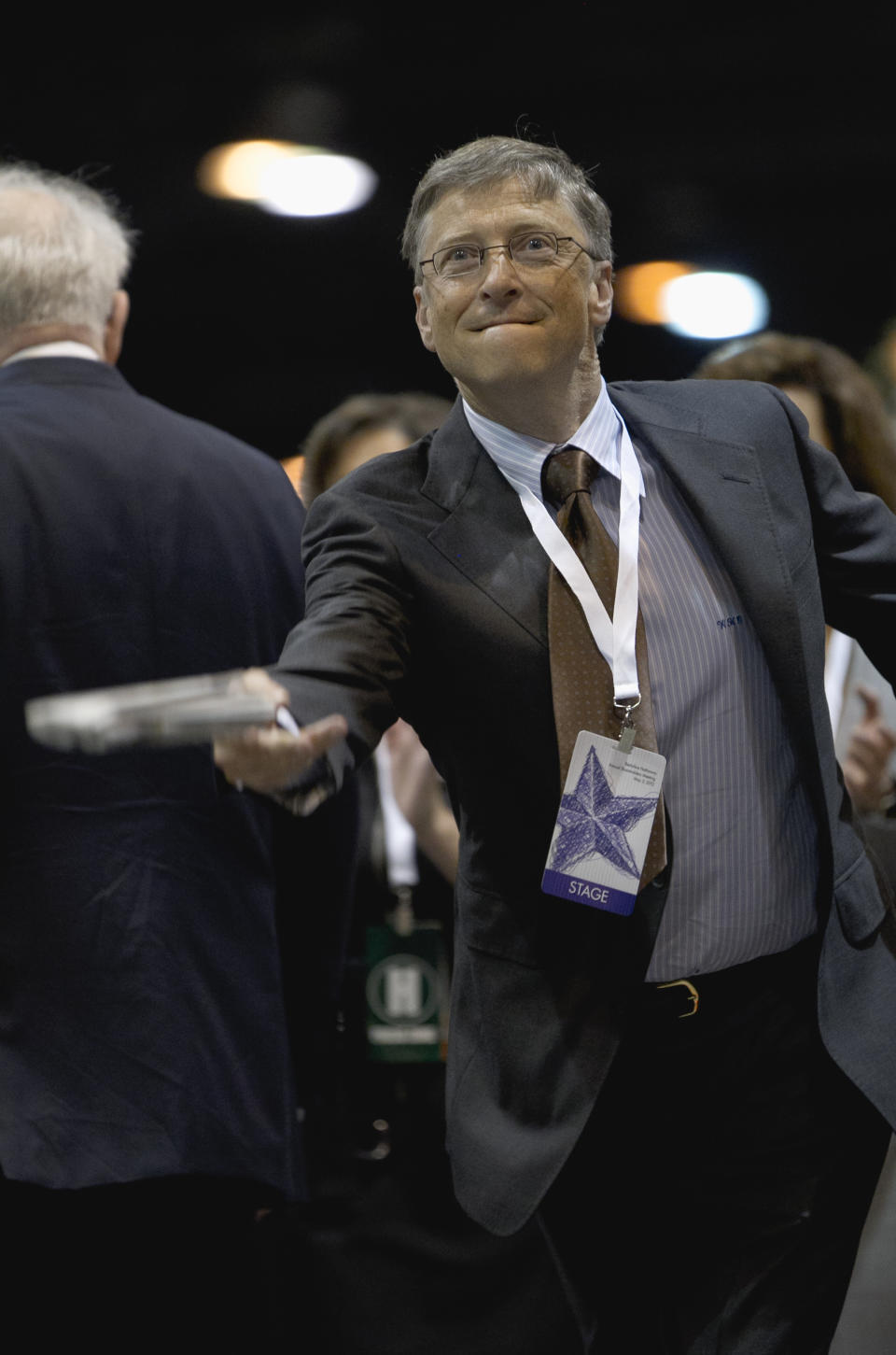 Bill Gates, a director with Berkshire Hathaway, tosses a newspaper during a newspaper tossing competition in Omaha, Neb., Saturday, May 5, 2012. Berkshire Hathaway is holding it's annual shareholders meeting this weekend. (AP Photo/Nati Harnik)