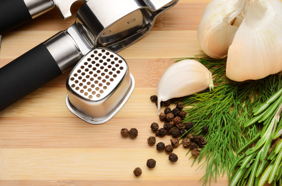 garlic and spices with garlic press on a chopping board