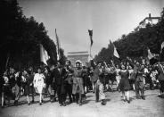 <p>Crowds filled with both servicemen and civilians celebrate the defeat by marching down the Champs Élysées waving banners and flags. </p>