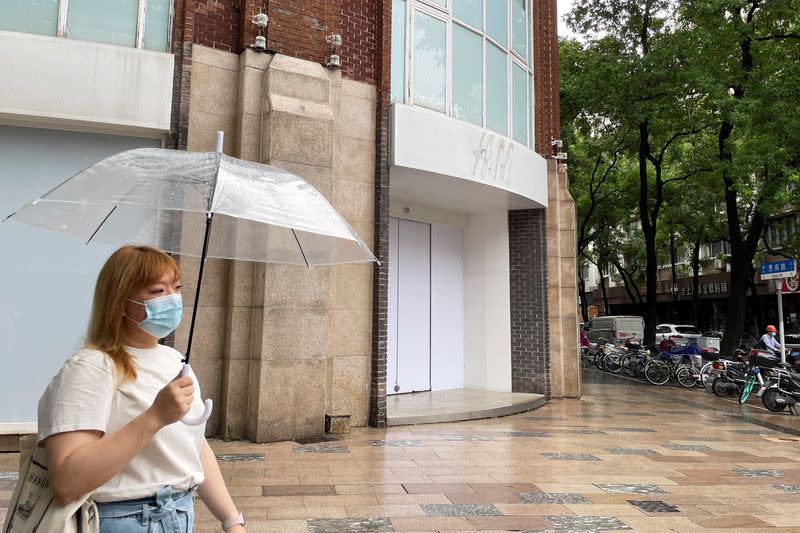 FILE PHOTO: Woman walks past a closed H&M flagship store in Shanghai