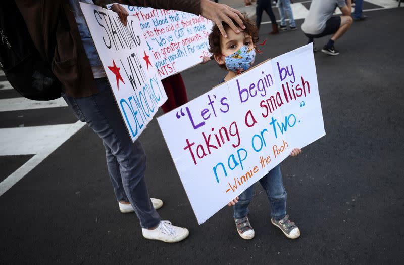 A kid wearing a face mask holds a sign at Black Lives Matter Plaza near the White House after Election Day in Washington