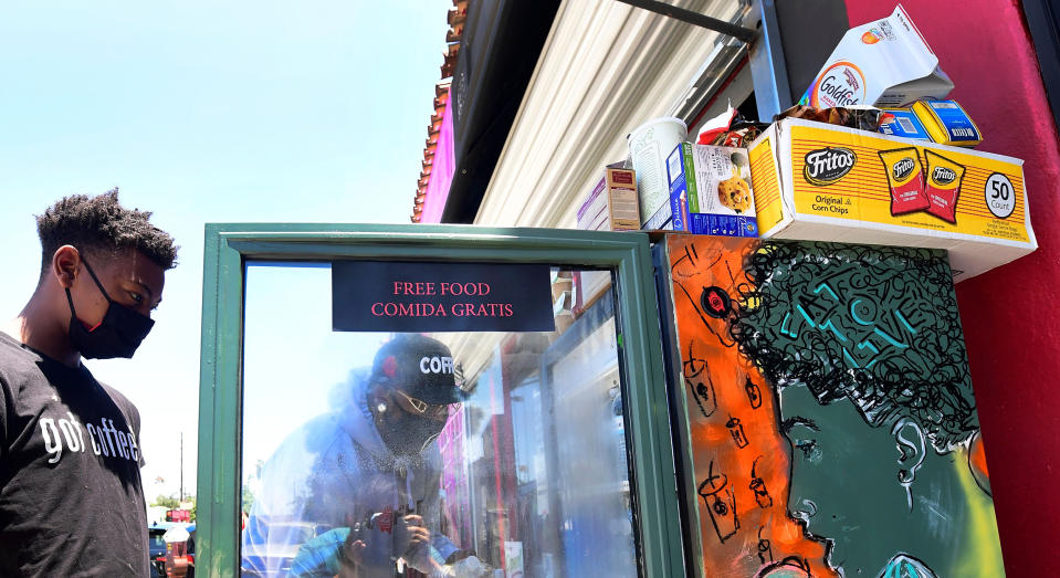 Image: Solo Morris holds the fridge door open as Danny Dierich stocks it with more items on July 16, 2020 outside the Little Amsterdam Coffee shop in Los Angeles. (Frederic J. Brown  / AFP via Getty Images file)
