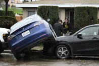 Residents move furniture from a home damaged by flooding next to cars moved by the waters during a rainstorm Monday, Jan. 22, 2024, in San Diego. (AP Photo/Denis Poroy)