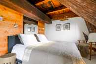<p>There are three bedrooms in total. This one has plenty of rustic charm with its wood paneling and beamed ceiling. (Airbnb) </p>