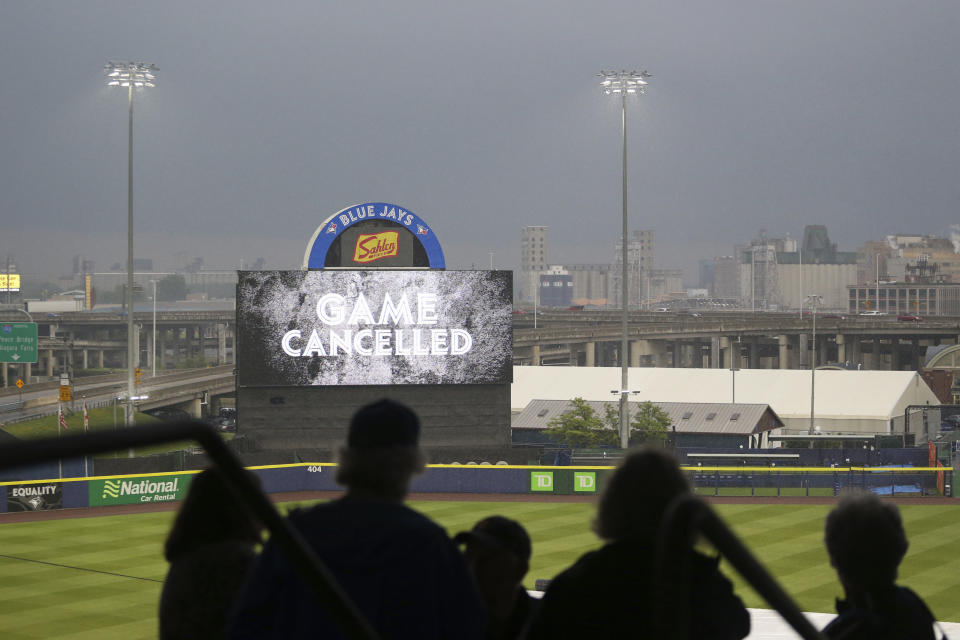 Fans and stadium staff look at the scoreboard after the baseball game between the Toronto Blue Jays and Boston Red Sox was postponed Tuesday, July 20, 2021, in Buffalo, N.Y. (AP Photo/Joshua Bessex)