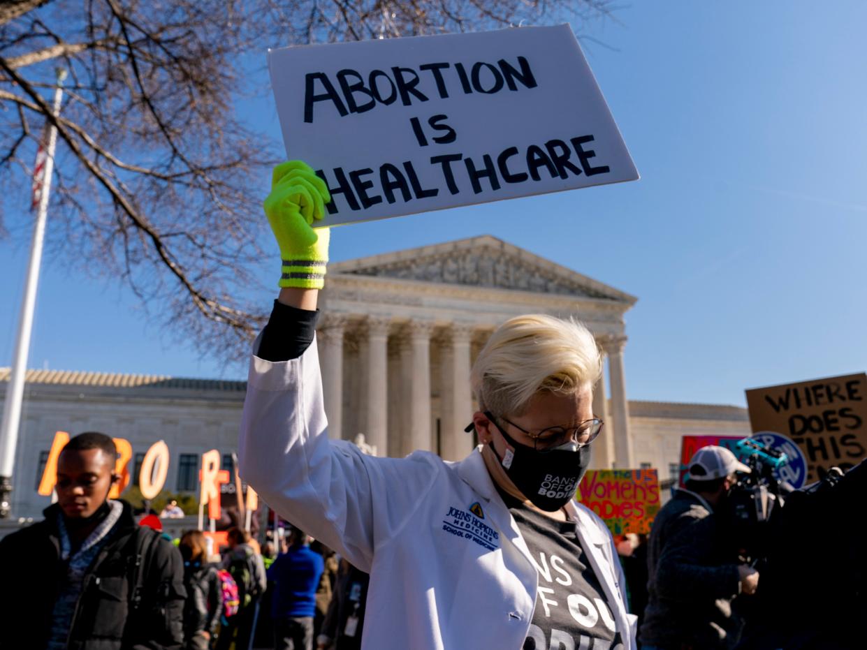 A woman holds a poster that reads "Abortion is Healthcare" as abortion rights advocates and anti-abortion protesters demonstrate in front of the U.S. Supreme Court, Dec. 1, 2021, in Washington, as the court hears arguments in a case from Mississippi, where a 2018 law would ban abortions after 15 weeks of pregnancy, well before viability.