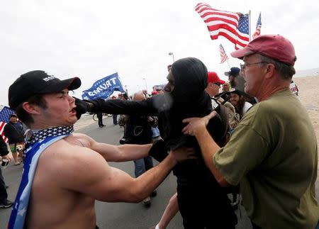 A pro-Trump rally participant is punched in the face by an anti-Trump protester as the two sides clash at a Pro-Trump rally in Huntington Beach, California, U.S., March 25, 2017. REUTERS/Patrick T. Fallon