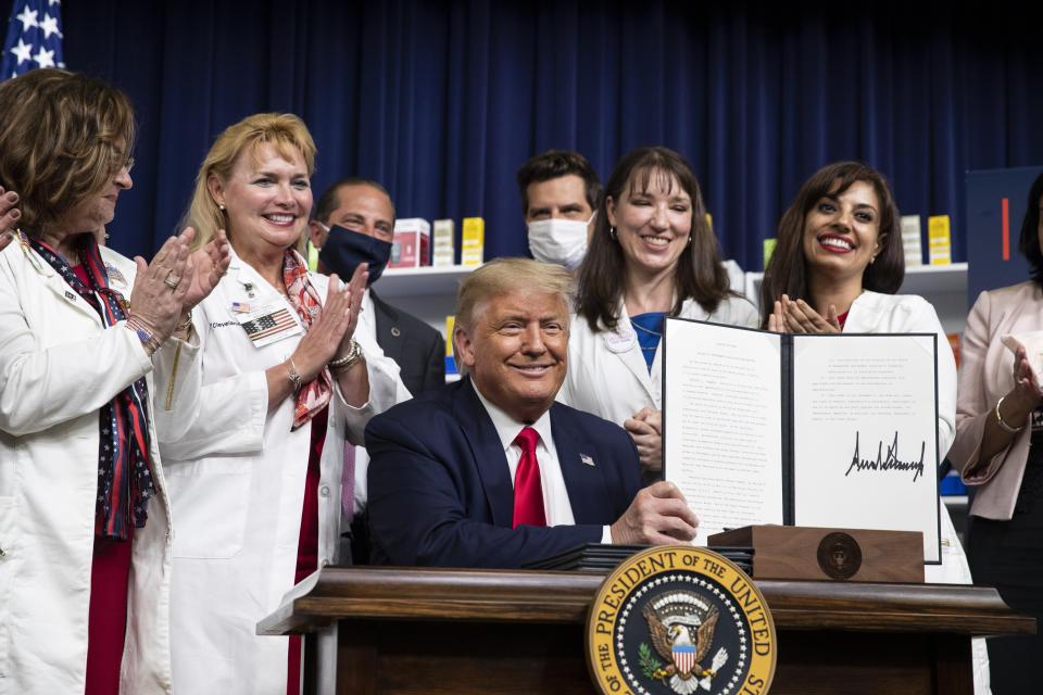 President Donald Trump holds up a signed executive order on lowering drug prices, in the South Court Auditorium in the White House complex, Friday, July 24, 2020, in Washington. (AP Photo/Alex Brandon)