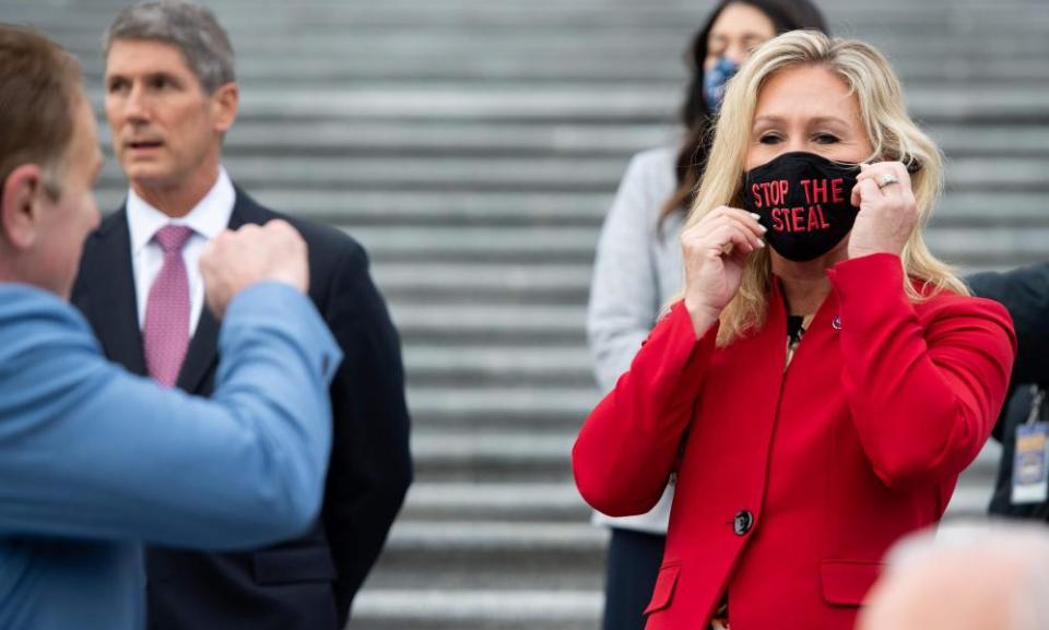 Marjorie Taylor Greene, Republican of Georgia, holds up a Stop the Steal mask while speaking with fellow first-term Republican members of Congress.