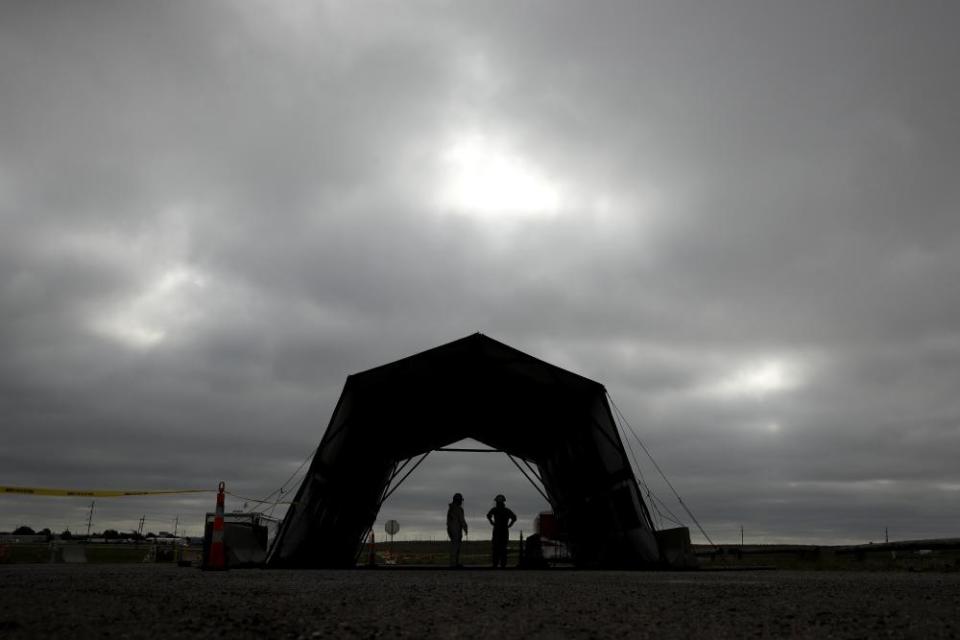 Guard members wait for cars during a lull in people seeking tests at a drive-thru COVID-19 testing site in Dodge City, Kan.