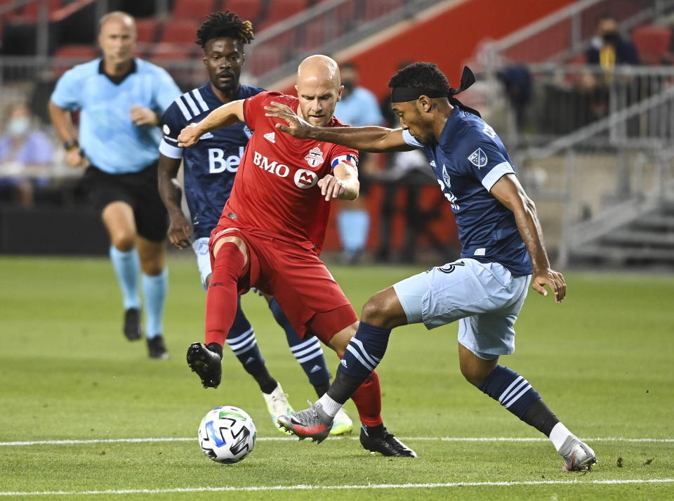 Toronto FC midfielder Michael Bradley (4) battles for the ball against Vancouver Whitecaps defender Derek Cornelius (13) during the first half of an MLS Canadian Championship soccer game in Toronto on Friday, Aug. 21, 2020. (Nathan Denette/The Canadian Press via AP)