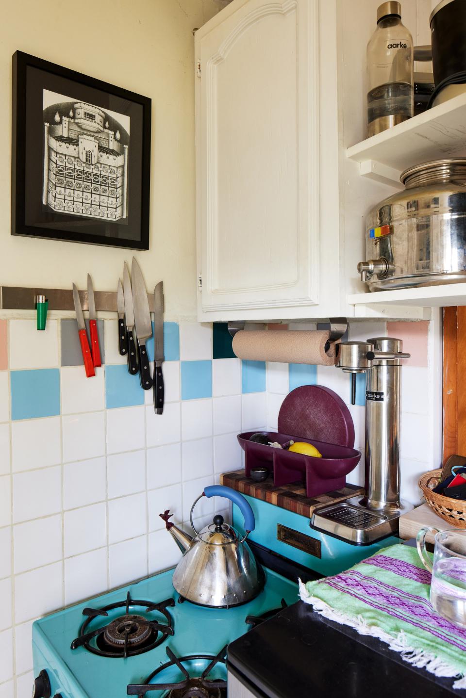 Jesse Hammer managed to squeeze in an eggplant-colored Fort Standard fruit bowl, a Felipe Lopez cutting board, and a Michael Graves Whistling Bird tea kettle in their tiny kitchen space.