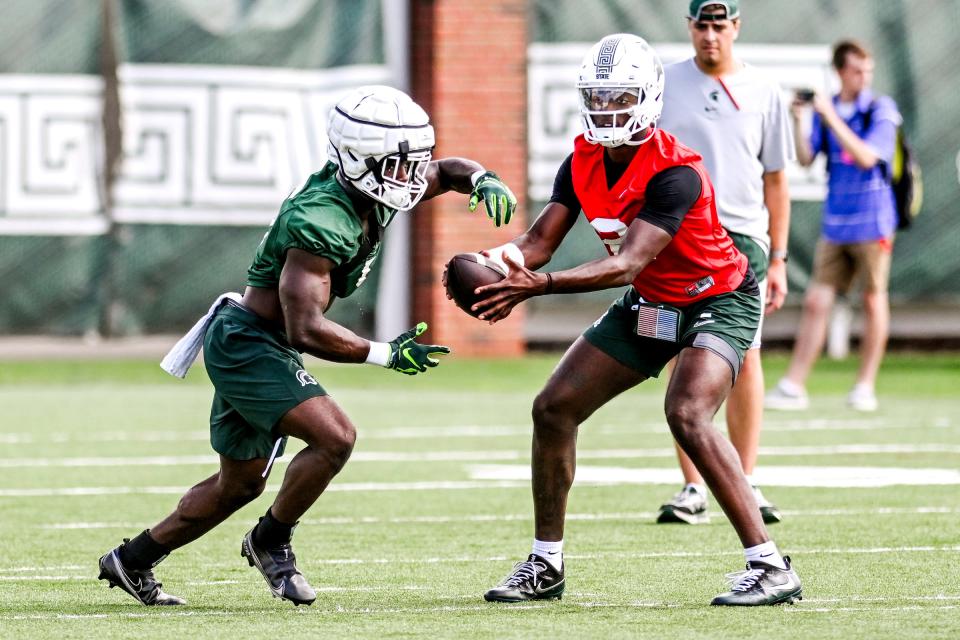 Michigan State's Nathan Carter, left, takes a handoff from quarterback Aidan Chiles during the first day of football camp on Tuesday, July 30, 2024, in East Lansing.