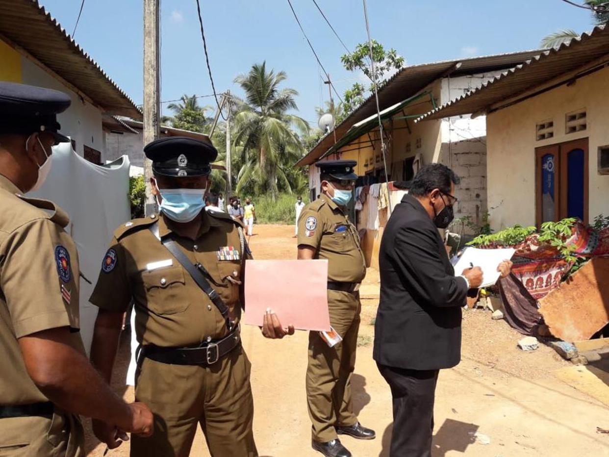 Sri Lankan magistrate Wasantha Ramanayake (right) and police officers inspect outside a house where a nine year old girl was canned to death in Delgoda, Sri Lanka, Sunday, Feb.28, 2021. 