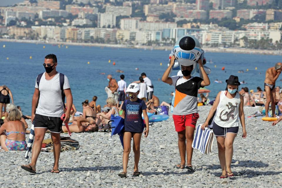 Tourists wearing protective face masks walk on the beach in Nice: REUTERS