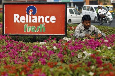 A gardener works next to a board of Reliance Fresh, a chain operated by Reliance Industries Ltd. retail arm, in Ahmedabad, India, January 19, 2016. REUTERS/Amit Dave