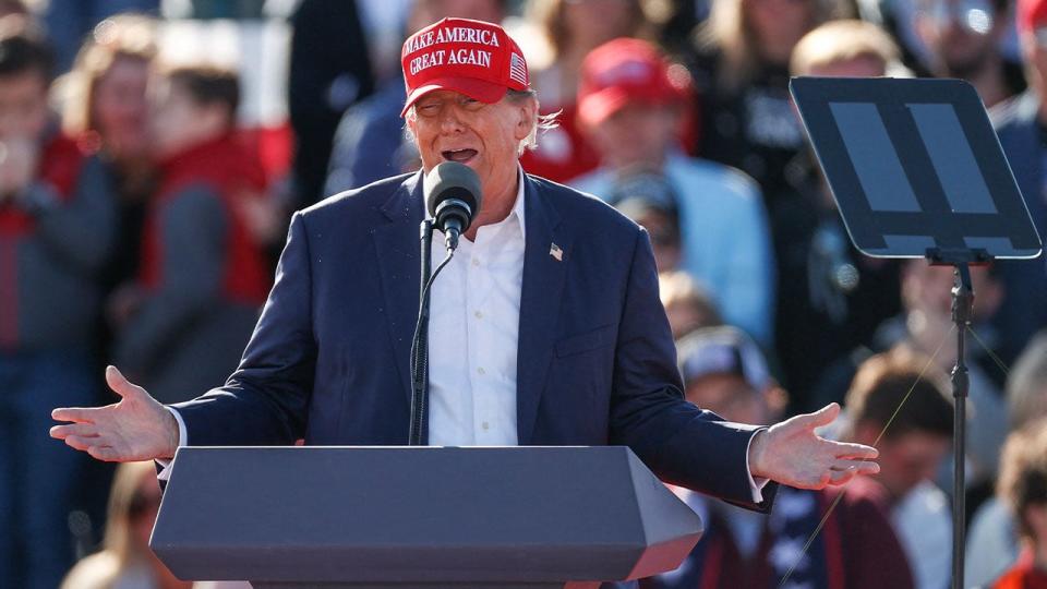 Donald Trump in red MAGA hat at outdoor rally