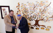 Jeff Cohen, left, and Lawrence Schwartz look at a cell phone together in the lobby of Congregation Beth Israel in Colleyville, Texas, Thursday, April 7, 2022. Three months after an armed captor took them hostage at the Texas synagogue, the house of worship is reopening. (AP Photo/LM Otero)