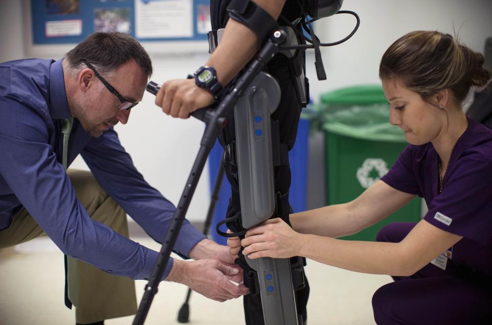 Allan Kozlowski (L), assistant professor of Rehabilitation Medicine at Icahn School of Medicine at Mount Sinai hospital, and Alexandra Voigt, a clinical research coordinator and therapist, adjust a ReWalk electric powered exoskeletal suit before a therapy session with 22-year-old Errol Samuels from Queens, New York, who lost the use of his legs in 2012 after a roof collapsed onto him, at Mount Sinai Hospital in New York March 26, 2014. ReWalk, made by the Israeli company Argo Medical Technologies, is a computer controlled device that powers the hips and knees to help those with lower limb disabilities and paralysis to walk upright using crutches. Kozlowski, whose patients are working with the ReWalk and another exoskeleton, the Ekso (Ekso Bionics) hopes machines like these will soon offer victims of paralysis new hope for a dramatically improved quality of life and mobility. The ReWalk is currently only approved by the U.S. Food and Drug Administration (FDA) for use in rehabilitation facilities like at Mount Sinai, as they weigh whether to approve the device for home use as it already is in Europe. Picture taken March 26, 2014. REUTERS/Mike Segar