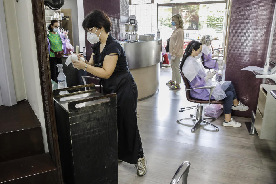 Hairdresser Piera Delogu cleans her hairstyling shop, in Milan, Italy, Monday 18, May 15, 2020. Italy is slowly easing its strict sanitary measures against the spread of coronavirus. (AP Photo/Luca Bruno)