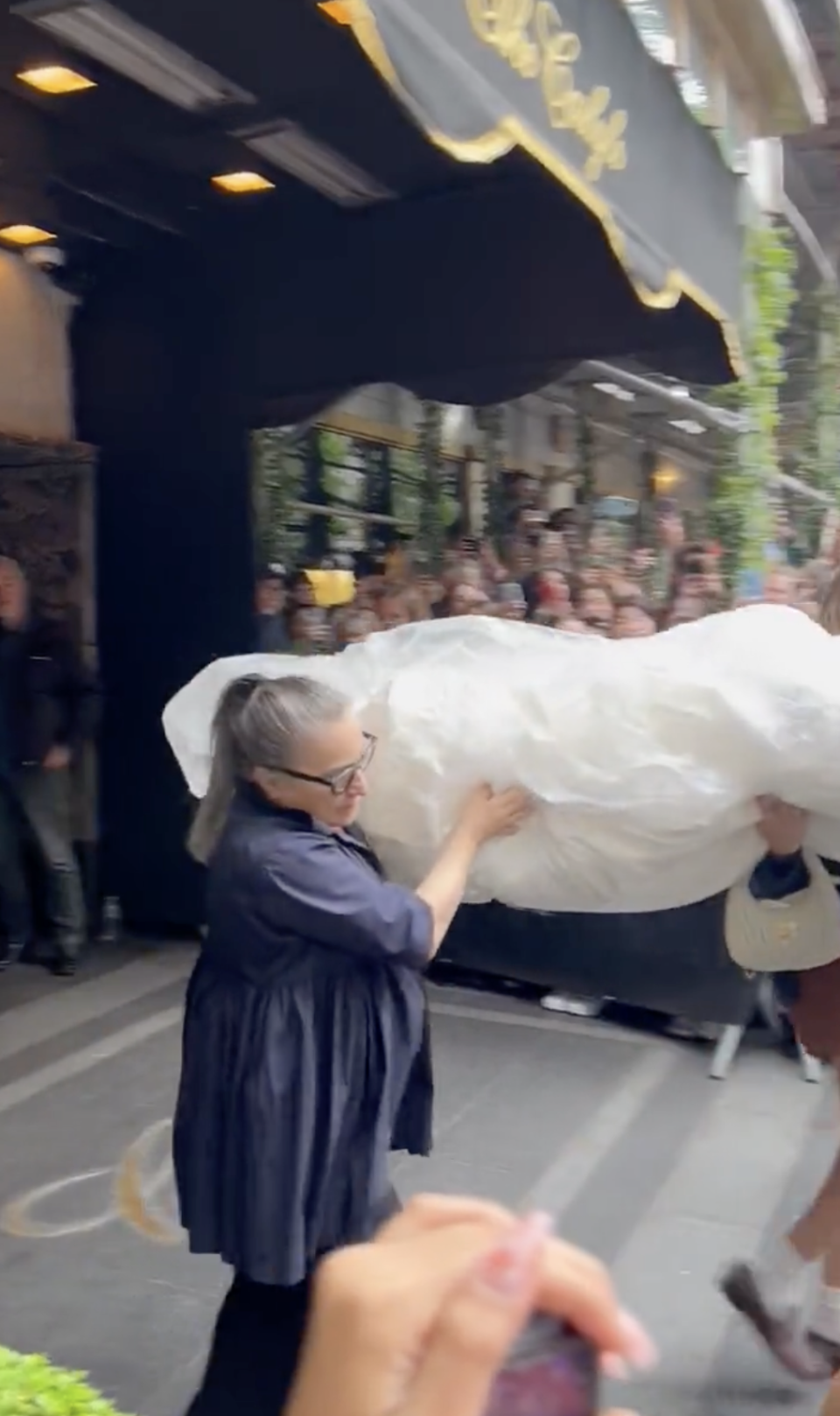 A crowd looks on at the bag is being carried out of The Carlyle hotel