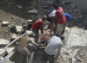 Volunteers carry the dead body of a plane crash victim at the site of a crash in Karachi, Pakistan, Friday, May 22, 2020. An aviation official says a passenger plane belonging to state-run Pakistan International Airlines carrying more than 100 passengers and crew has crashed near the southern port city of Karachi. There were no immediate reports on the number of casualties. (AP Photo/Fareed Khan)