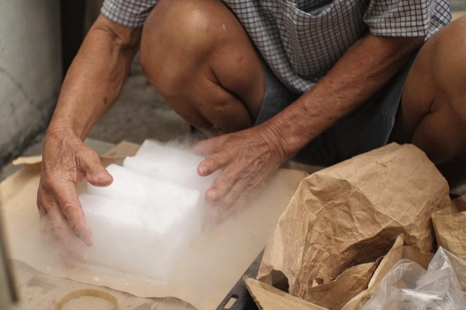 An elderly man handling dry ice with his bare hands.