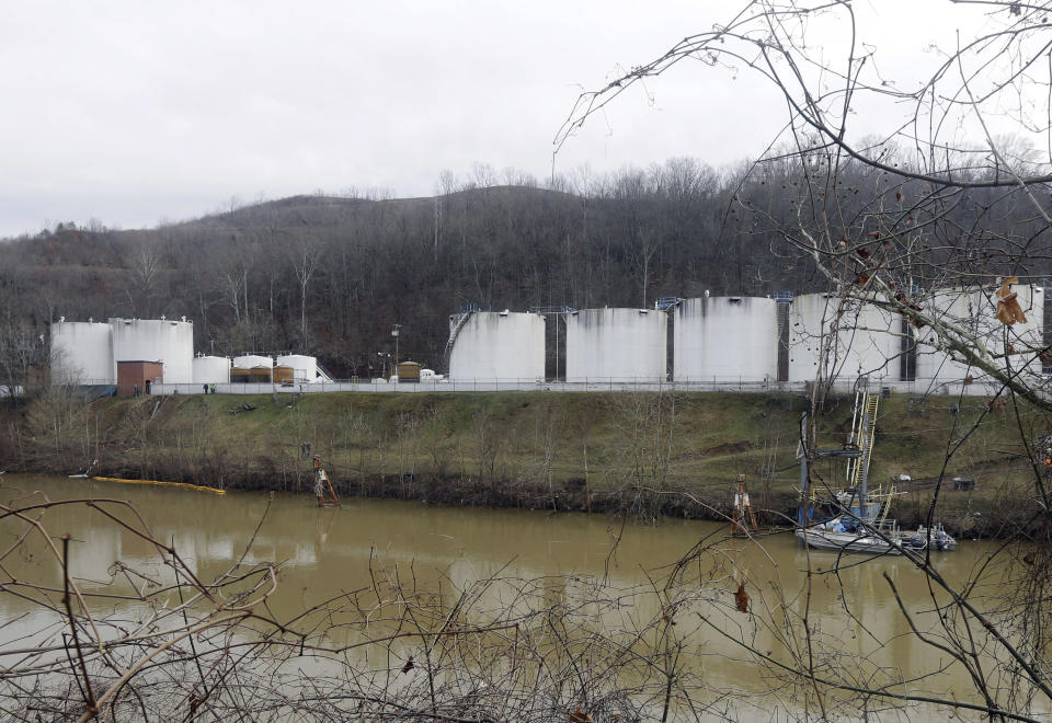 FILE - In this Monday, Jan. 13, 2014, file photo, workers,left, inspect an area outside a retaining wall around storage tanks where a chemical leaked into the Elk River at Freedom Industries storage facility in Charleston, W.Va. Department of Environmental Protection spokesman Tom Aluise says inspectors found five violations Monday at a Nitro, W.Va., site where Freedom Industries moved its coal-cleaning chemicals after last Thursday's spill. Inspectors found that, like the Charleston facility where the leak originated, the Nitro site lacked appropriate secondary containment. In Charleston, a porous containment wall allowed the chemical to ooze into the Elk River. (AP Photo/Steve Helber, File)