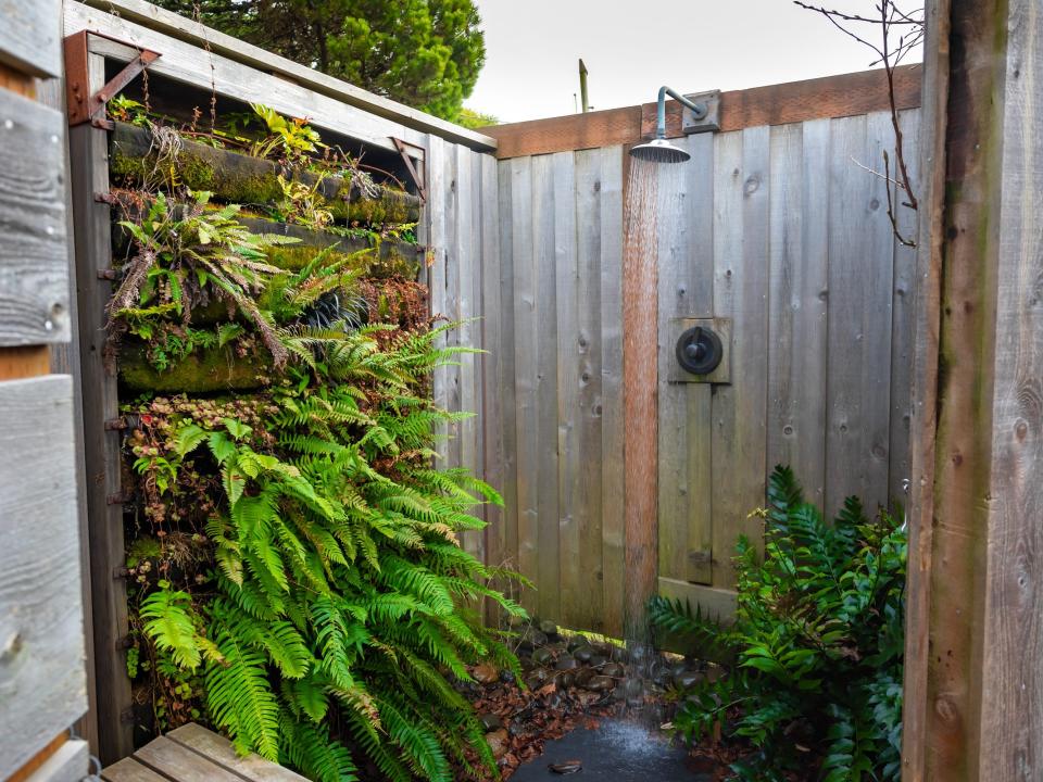 wood outdoor shower with plants in it