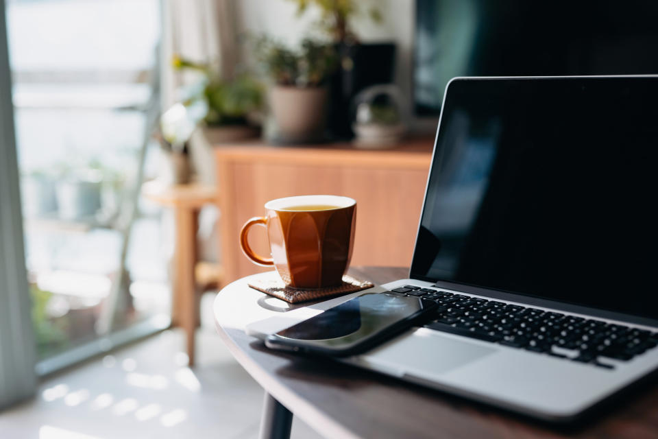 A cup of coffee, a phone, and a laptop