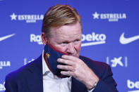 Ronald Koeman takes of his protective face mask during his official presentation as coach for FC Barcelona in Barcelona, Spain, Wednesday, Aug. 19, 2020. Barcelona officially announced earlier on Wednesday a deal with Koeman to become their coach five days after the team's humiliating 8-2 loss to Bayern Munich in the Champions League quarterfinals. Barcelona says the former defender's deal runs through June 2022. Koeman replaces the fired Quique Setien. (AP Photo/Joan Monfort)