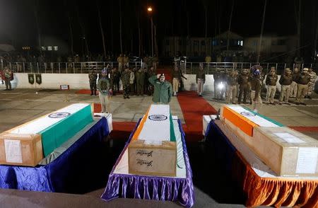 A senior officer of India's Central Reserve Police Force (CRPF) salutes in front of coffins containing the bodies of three colleagues, who were killed during a gunbattle with suspected militants at CRPF training centre, in Lethpora in south Kashmir’s Pulwama district, December 31, 2017. REUTERS/Danish Ismail