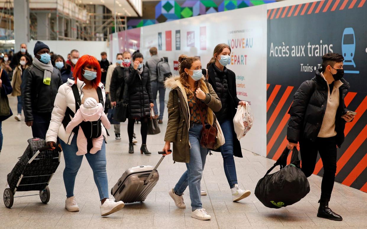 Passengers wearing protective face masks walk to board a train at Paris's Montparnasse railway station to go to the provinces to avoid the third lockdown imposed in the capital. - Chesnot