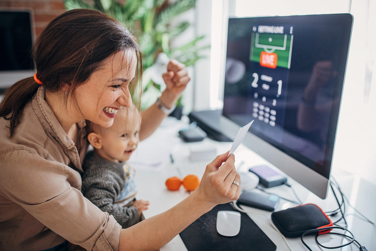 Two people, mother businesswoman and her baby boy son together in modern office at home. They are sports betting online together.