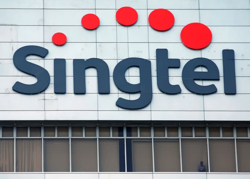 FILE PHOTO A man looks out of the window under a Singtel signage at their head office in Singapore