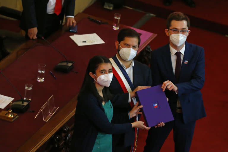 El presidente chileno Gabriel Boric, en el centro, sostiene el borrador final de la nueva constitución del país junto con los miembros de la Convención Constituyente, María Elisa Quinteros y Gaspar Domínguez, en Santiago, Chile, el lunes 4 de julio de 2022. (AP Foto/Luis Hidalgo)